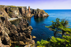 Steep coastal cliffs and deep blue ocean waters along Spiller's Cove near Witless Bay boat tour route.